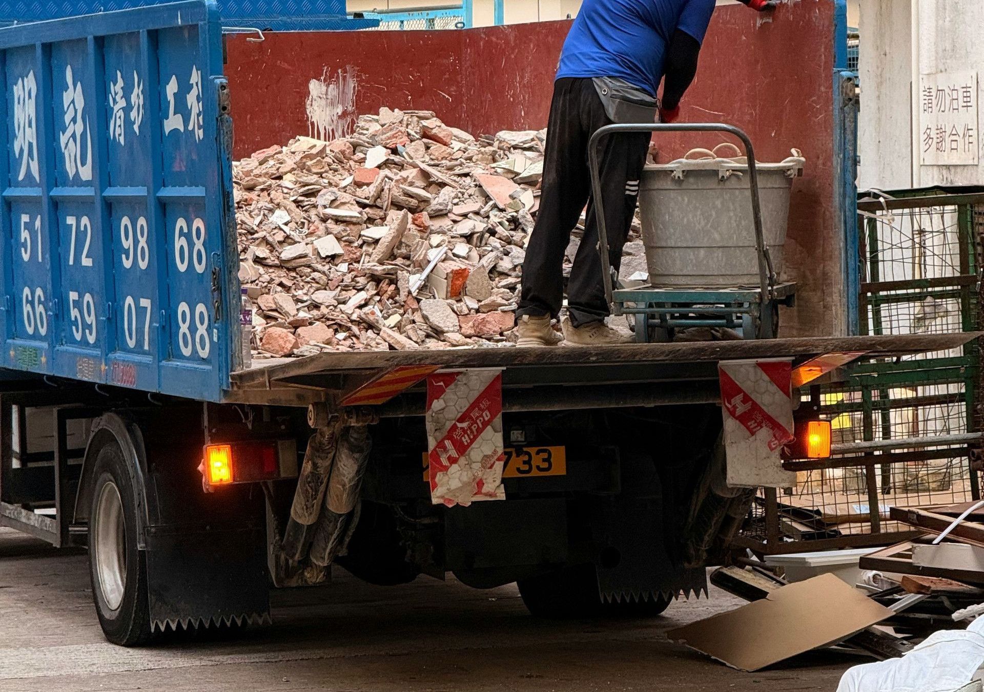 Worker loading debris into a blue truck