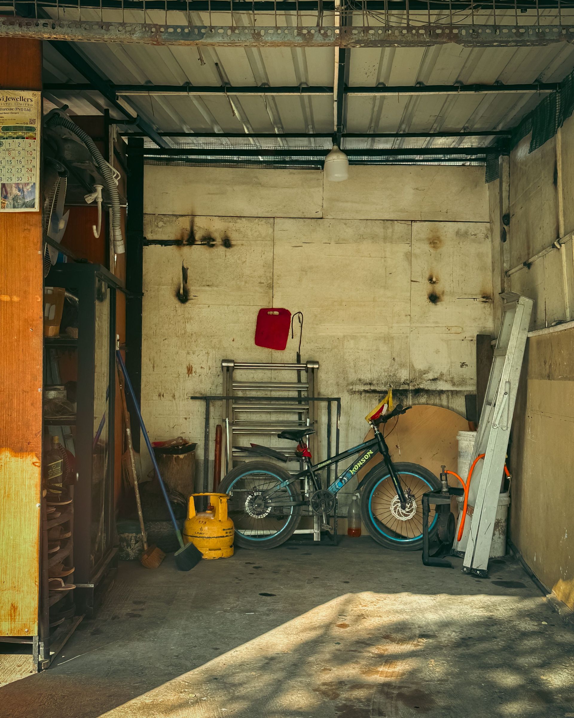 A tidy garage setup featuring a bicycle, ladder, and various tools against a rustic wall.